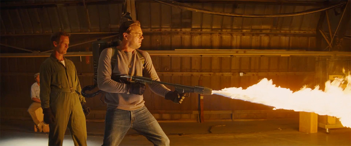 A man firing a flamethrower across a warehouse.